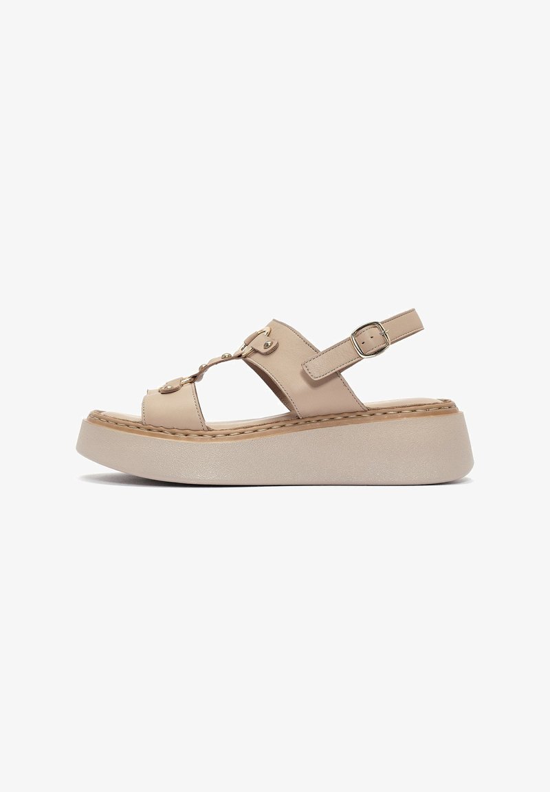 Beige platform sandals with a smooth leather upper, adjustable ankle strap, and decorative gold-tone hardware; closed toe design.