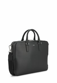 Malette en cuir noir avec une finition texturée, quincaillerie en argent, deux poignées supérieures, une bandoulière amovible et une fermeture éclair.