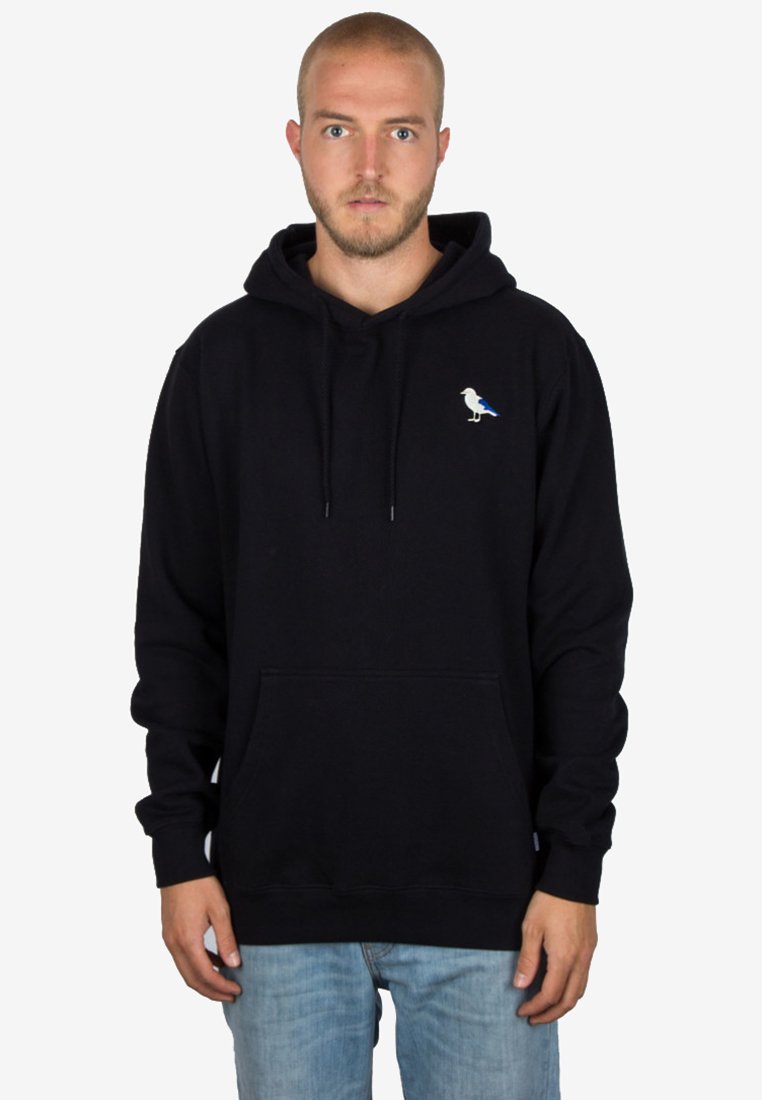 Sudadera negra con bolsillo canguro en el frente, que presenta un pequeño gráfico de un pájaro en blanco y azul en el área del pecho izquierdo. Material de algodón.
