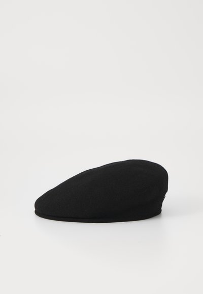 Boina de lana negra, forma redondeada, textura suave, con una parte superior plana y un pequeño borde. Diseño simple sin acentos o patrones visibles.
