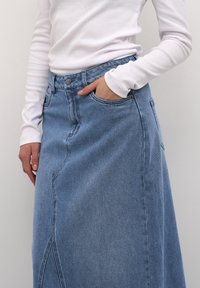 Blue denim midi skirt with a high waist, side pocket, and stitched detailing. The fabric has a smooth texture and slight faded finish.
