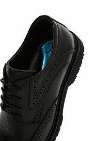 Chaussure habillée en cuir noir avec un design perforé détaillé, lacets plats et semelle intérieure rembourrée dotée d'accents bleus. Semelle en caoutchouc.