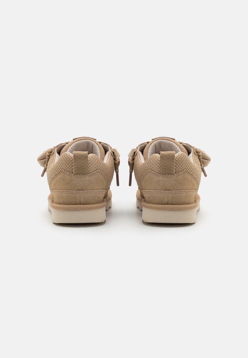 Helle Wildlederschuhe mit glatter Textur, mit Stoffapplikationen und Schleifen an der Rückseite, runder Zehenform und einer hellen Gummisohle.