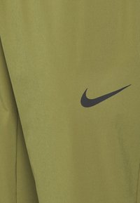 Nike Sportbekleidung aus olivgrünem Stoff, mit einem eleganten Design, glatter Textur und einem auffälligen schwarzen Nike-Swoosh-Logo.