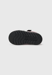 Sko såle med svart gummimateriale, med et strukturert bølgemønster og preget "PUMA"-logo; hvit ytterkant.