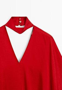 Rode blouse met een diepe V-hals en een colliersluiting. Heeft een knoopsluiting aan de achterkant en een soepel materiaal voor een ontspannen silhouet.