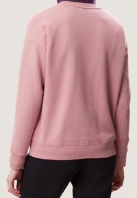 Felpa rosa con polsini e orlo a costine, caratterizzata da una morbida texture e un design semplice. Piccolo dettaglio con logo sul retro, all'altezza del collo.