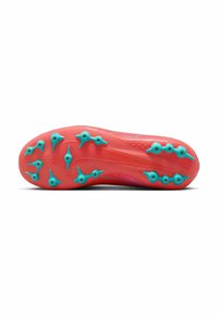 Suela de zapatilla de fútbol roja con tapones moldeados azules; superficie texturizada con líneas y surcos para tracción. Diseño distintivo para un rendimiento en césped artificial.