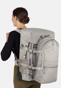 Grau Stoff-Rucksack mit mehreren Fächern, Netzakzenten und verstellbaren Riemen. Verfügt über Rollen für einfachen Transport.