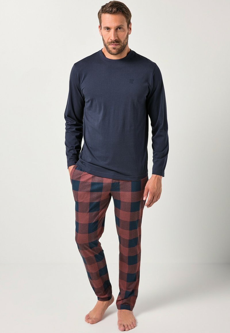 Camisa de manga larga marina combinada con pantalones de pijama a cuadros en marrón y azul marino, con un corte relajado y tela suave. No se llevan zapatos.