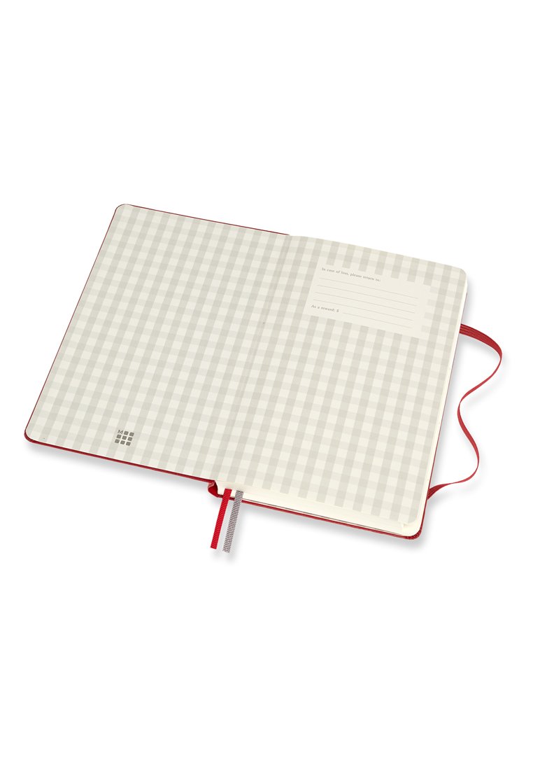 Cuaderno abierto con un patrón de cuadros beige en la cubierta interior, una etiqueta de dirección de retorno y marcadores de cinta rojos y blancos sobre un fondo blanco.