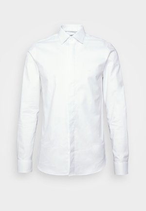 White long-sleeve shirt made of smooth cotton fabric. Features a classic collar, button placket, and fitted design with cuffs at the wrists.