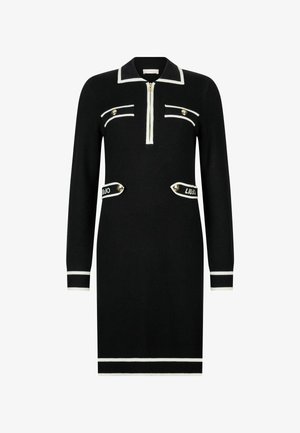 Czarna długa sukienka z długim rękawem i kołnierzem na zamek, białe akcenty, dwie przednie kieszenie oraz złote guziki; prążkowane mankiety i dół.