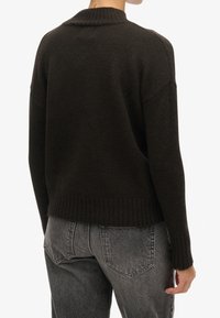 Pull en tricot brun foncé avec col et ourlet côtelés, présentant des épaules tombantes et une coupe décontractée, vu de dos.