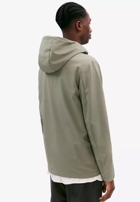 Waterdichte groene gewatteerde jas met een gladde textuur, met een minimalistisch design en een relaxte pasvorm. Achteraanzicht toont de naaddetails.