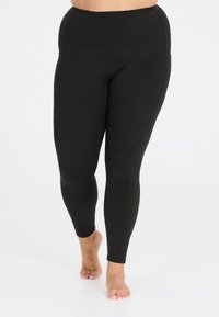 Zwarte leggings met een hoge tailleband, gemaakt van rekbaar materiaal. Beschikt over een soepele textuur en zijzakken. Strak aansluitend ontwerp.
