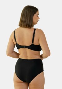 Ensemble de bikini noir en tissu doux et extensible. Le haut possède des bretelles réglables et une fermeture à crochet, tandis que le bas est taille haute.