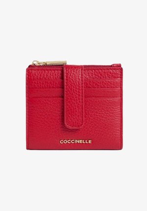 Portafoglio in pelle rossa con texture, cerniera dorata, scomparti per carte e fascia frontale, con marchio "Coccinelle" in scritta dorata.
