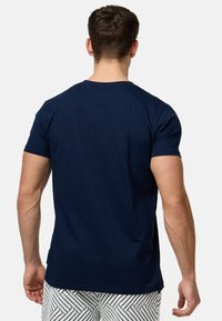 T-shirt bleu marine à manches courtes avec col rond, fabriqué en tissu doux et texturé, présentant une coupe droite et des détails de couture minimaux.