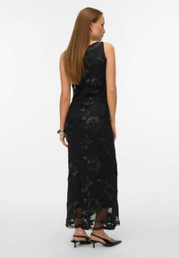 Černé maxi šaty s květinovou výšivkou, bez rukávů, průsvitná textura a lehce splývavý střih. Nošeny s černými lodičkami na stélce za patu.