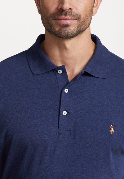 Marineblå polo skjorte med klassisk krage, tre knapplukking og brodert logo på brystet. Laget av strukturert bomullsstoff.