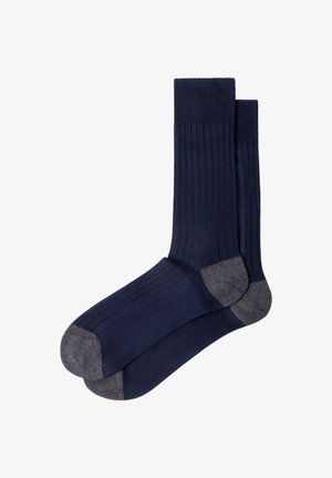 Coppia di calzini blu navy a coste con accenti grigio scuro su tacco e punta, posati in piano e sovrapposti con uno leggermente sopra l'altro.