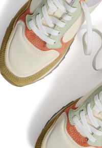 Zapatillas con un upper de color crema y acentos en durazno, verde y olivo. Materiales de gamuza texturizada y nailon con cordones blancos.