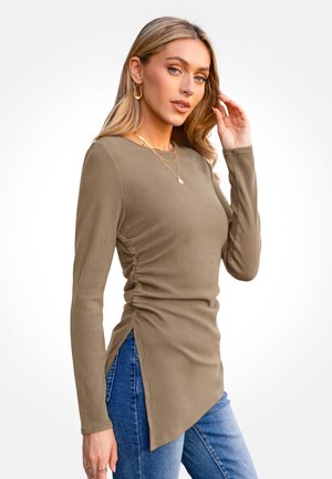 Top a coste verde oliva a maniche lunghe con spacchi laterali e scollo rotondo, abbinato a jeans blu. La texture è morbida e aderente.