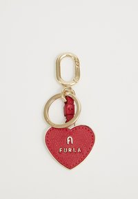 Crvena kožna privjesak u obliku srca s utisnutim logotipom "FURLA" i zlatnim detaljima, koji sadrži privjesak za ključeve i teksturiranu površinu.