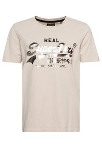 Beige bavlněné tričko s tištěným stříbrným/černým logem a textovým designem "SuperDry". Krátké rukávy a kulatý výstřih.