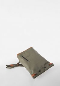 Zaino verde oliva con dettagli marroni, dotato di una tasca con cerniera e spallacci regolabili, realizzato in materiale resistente, con una texture liscia.