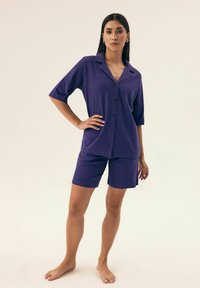 Fioletowy zestaw szortów i krótkiego rękawa koszuli z miękkiego materiału; posiada kołnierzyk i luźny krój.
