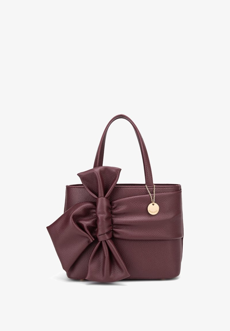 Borsa in pelle borgogna con texture, dotata di un grande fiocco su un lato e un charm dorato attaccato a una catena. Manici doppi per il trasporto.