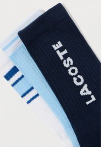 Trei perechi de șosete de echipă: bleumarin cu logo-ul alb „LACOSTE”, albastru deschis cu dungi și alb cu dungi albastre. Făcute din țesătură tricotată.