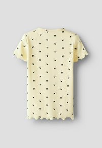 Geel geribbeld T-shirt met korte mouwen, voorzien van een zwart strikpatroon, geschulpte zoom en ronde halslijn. Het patroon herhaalt zich uniform over de stof.