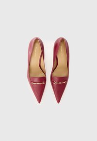 Røde skinnhøyhælte pumps med spiss tå, med en gullfarget kjededetalj over vampen og en glatt tekstur. Merke: Michael Kors.