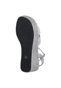Vit sandal med texturerat rem och glittrig silverklack. Har en svart sula och silverdetaljer längs kanten. Storlek 39.