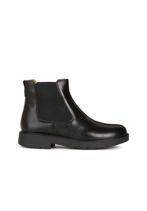 Schwarzer Leder-Chelsea-Boot mit elastischem Seitenteil und niedriger, klobiger Sohle, im Profil vor weißem Hintergrund gezeigt.