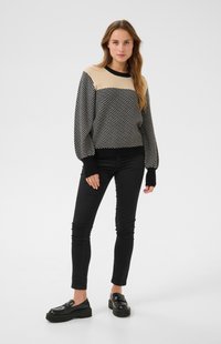 Mustard ja kooretriibuline sviiter ümarate kaelustega ja puffeered varrukatega, kombineeritud mustade slim-fit teksade ja tugeva musta loafritega.