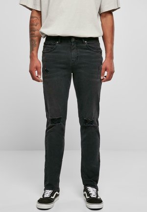 Jeansi negri din denim cu găuri distorsionate la genunchi, croială dreaptă, design cu cinci buzunare și decolorare subtilă. Asortați cu adidași negri și albi.