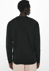 Schwarzes Langarmshirt aus Baumwolle, mit Rundhalsausschnitt und lässigem Schnitt. Glatte Textur, minimales Design ohne sichtbares Branding.