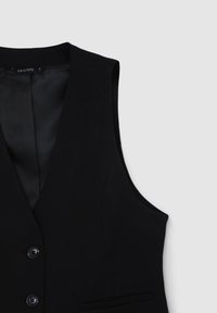 Gilet senza maniche nero in un tessuto liscio con colletto a punta, dotato di due bottoni frontali e di una sottile tasca sul lato sinistro.