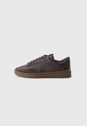 Brown leather sneakers with suede accents, textured surfaces, round toe, and flat brown rubber sole. Six eyelets and lace closure.