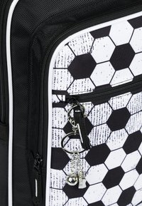 Zaino a tema calcistico bianco e nero con motivo esagonale, tasca con cerniera e charm staccabile che presenta un fischietto e una palla.