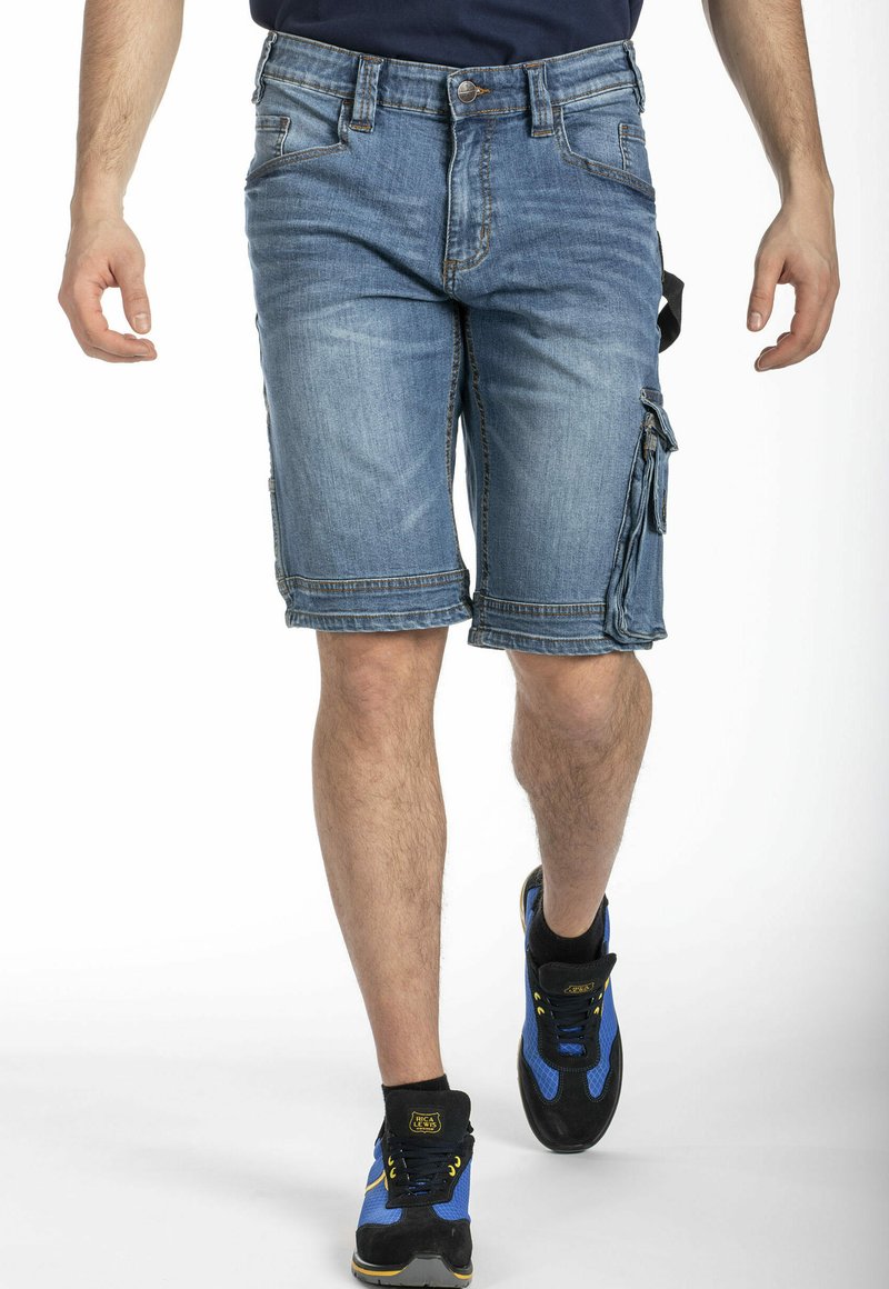 Shorts cargo en denim bleu clair, présentant une coupe régulière, plusieurs poches et des coutures contrastées, assortis à des baskets noires et bleues.