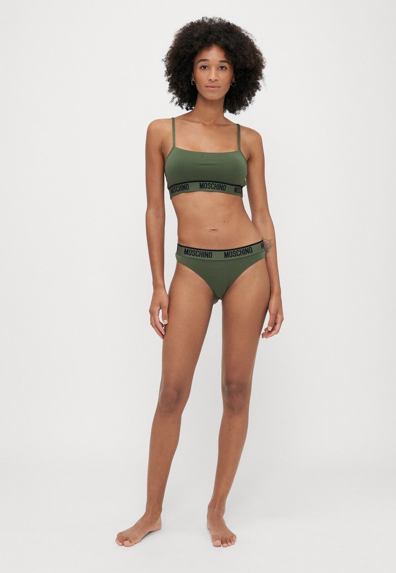 Bikini set iz olivno zelene bombažne mešanice, ki vključuje bralette z tankimi naramnicami in ujemajoče se visoke hlačke z detajlom črnega logotipa.