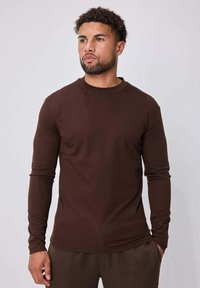T-shirt manches longues marron en tissu doux ; col rond, coupe ajustée et poignets sans coutures. Caractérisé par une texture lisse.