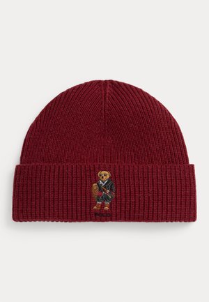 Gorro de malha canelada vermelha com bainha dobrada, apresentando um urso bordado com um fato preto e a palavra "POLO" embaixo.