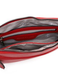 Interno della borsa a tracolla rossa in pelle, con fodera grigia, numerosi scomparti, una tasca con zip e una superficie liscia.