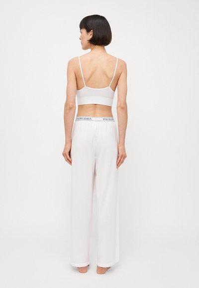Bralet alb cu bretele subțiri, asortat cu pantaloni albați cu pantaloni largi, având un brâu elastic negru. Textură a materialului neted.